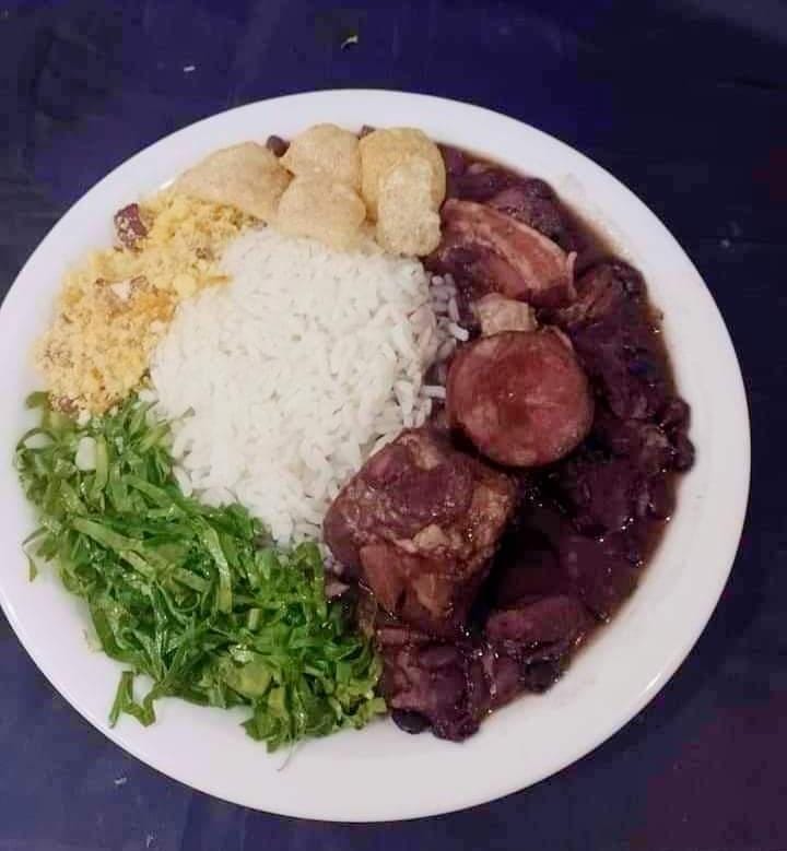 Prato de feijoada com arroz, farofa, torresmo e couve
